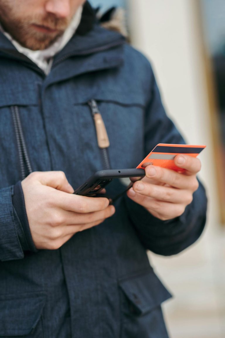 Anonymous guy with plastic card making online payment using smartphone on street